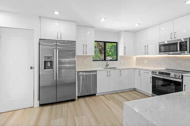 15687 Loch Maree Ln Unit 2404, Delray Beach, FL 33446 - kitchen featuring appliances with stainless steel finishes, modern cabinets, a sink, white cabinetry, and light wood-style flooring