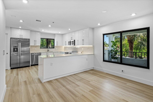 15687 Loch Maree Ln Unit 2404, Delray Beach, FL 33446 - kitchen with appliances with stainless steel finishes, a sink, light wood-type flooring, light countertops, and a peninsula