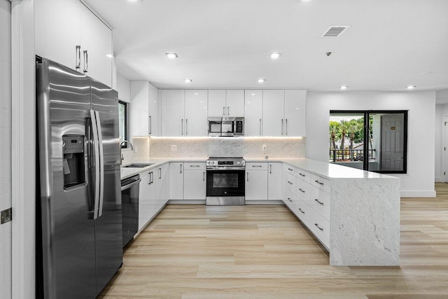 15687 Loch Maree Ln Unit 2404, Delray Beach, FL 33446 - kitchen with appliances with stainless steel finishes, a sink, a peninsula, light wood-style floors, and white cabinetry