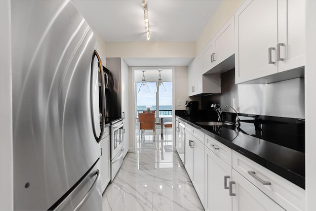 kitchen with marble finish floor, dark countertops, white cabinets, a sink, and appliances with stainless steel finishes