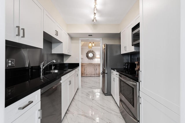 kitchen featuring dark countertops, a sink, marble finish floor, stainless steel appliances, and white cabinetry
