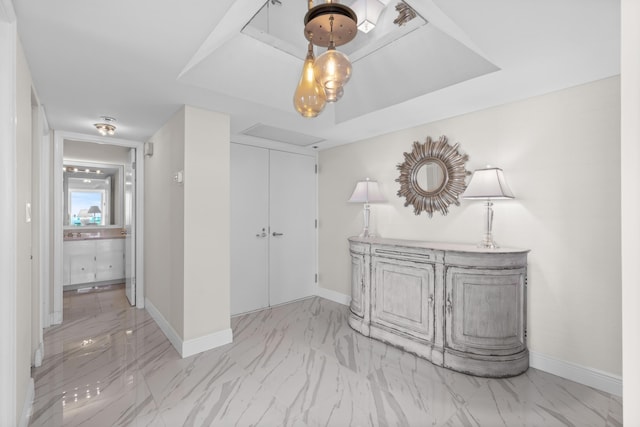 interior space featuring baseboards, marble finish floor, and a tray ceiling