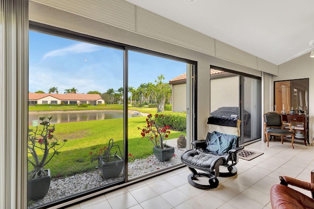 sunroom featuring a water view and a ceiling fan