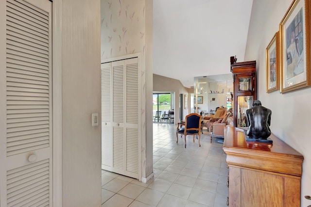 hall featuring light tile patterned floors and high vaulted ceiling