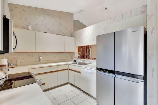 kitchen with stainless steel appliances, wallpapered walls, light tile patterned floors, and a sink