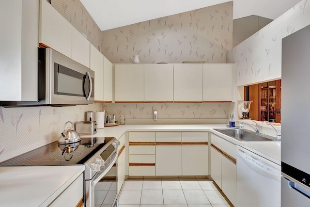 kitchen with light tile patterned flooring, appliances with stainless steel finishes, a sink, light countertops, and decorative backsplash