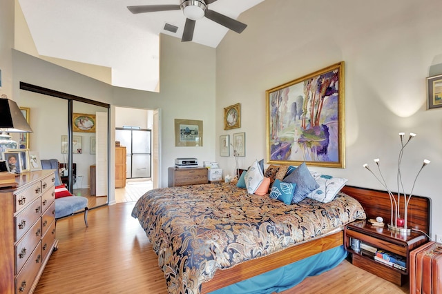 bedroom with visible vents, a ceiling fan, wood finished floors, and high vaulted ceiling