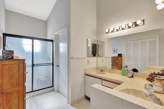 bathroom with a sink, double vanity, tile patterned floors, a shower stall, and a towering ceiling