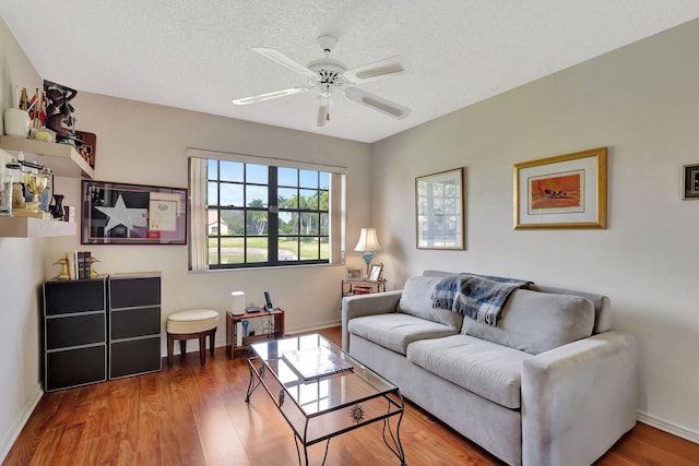living area with baseboards, ceiling fan, and wood finished floors