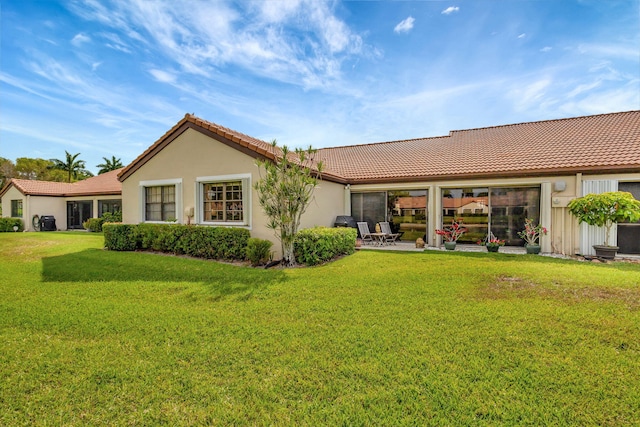 back of property featuring a lawn, stucco siding, a tile roof, and a patio