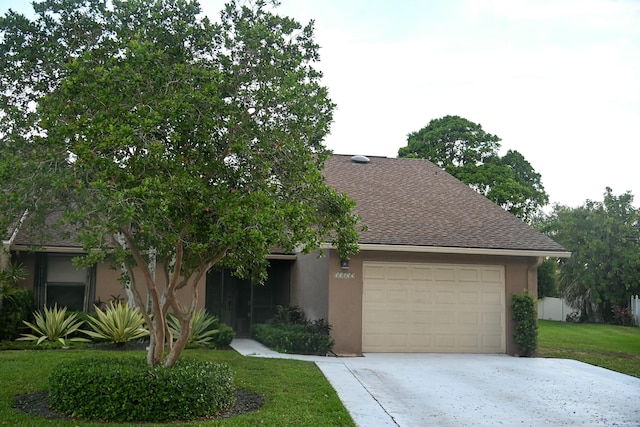view of front of house featuring a front yard, roof with shingles, a garage, concrete driveway, and stucco siding