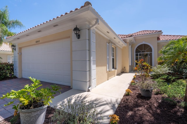 exterior space with a tiled roof, an attached garage, and stucco siding