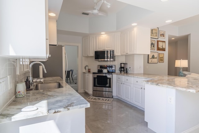 kitchen with a sink, stainless steel appliances, recessed lighting, a peninsula, and backsplash