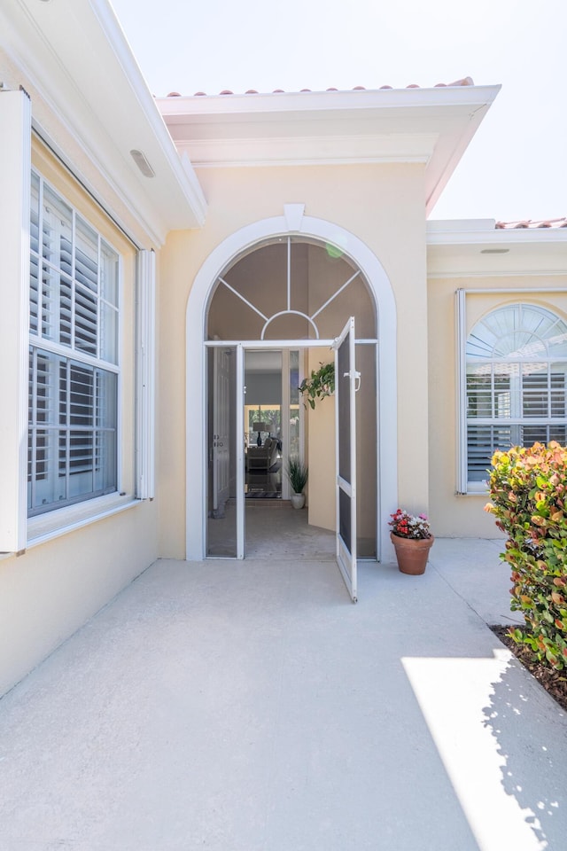 view of exterior entry with a patio area and stucco siding