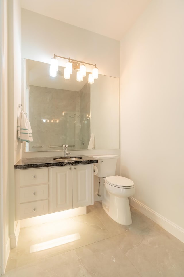 bathroom featuring toilet, baseboards, walk in shower, and vanity