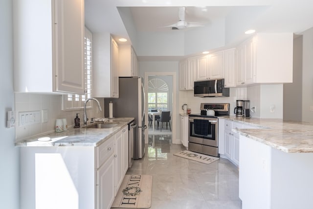 kitchen with a sink, appliances with stainless steel finishes, white cabinets, and tasteful backsplash