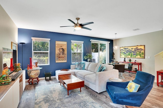 living room featuring baseboards, ceiling fan, visible vents, and wood finished floors