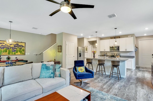 living area with visible vents, a ceiling fan, light wood finished floors, and recessed lighting