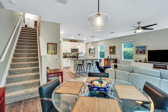 dining room featuring ceiling fan, visible vents, stairs, light wood-style floors, and recessed lighting