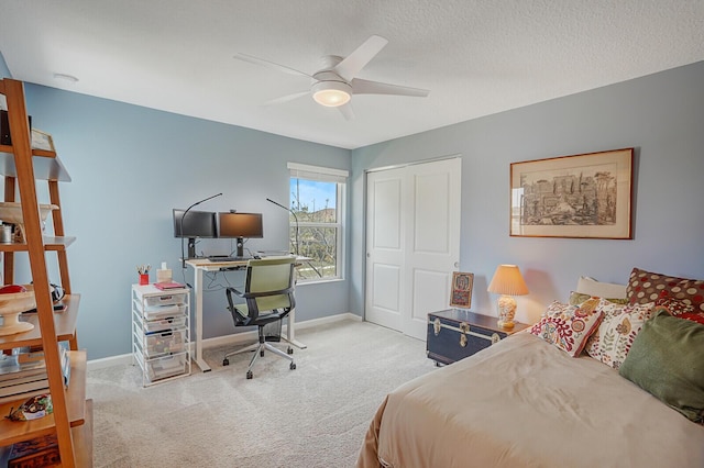 carpeted bedroom featuring a closet, a ceiling fan, baseboards, and a textured ceiling