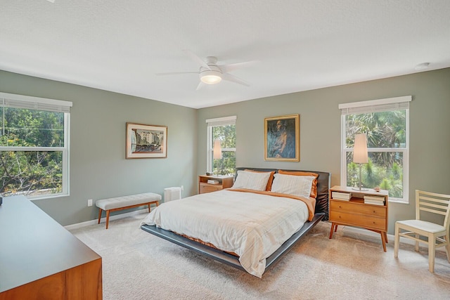 bedroom with light colored carpet, baseboards, and ceiling fan