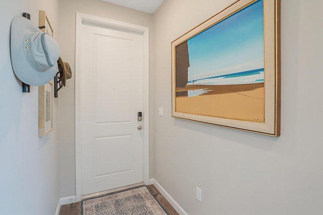 doorway featuring baseboards and wood finished floors