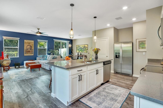 kitchen featuring appliances with stainless steel finishes, a sink, visible vents, and wood finished floors