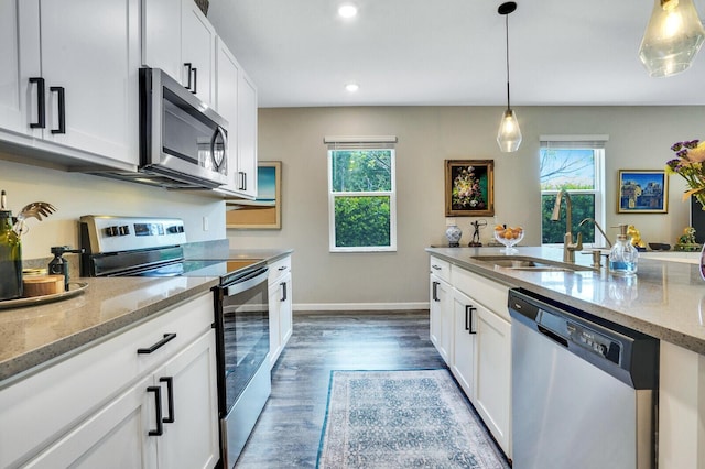 kitchen with a sink, appliances with stainless steel finishes, baseboards, and white cabinetry