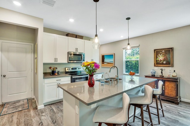 kitchen featuring visible vents, light wood-style floors, white cabinetry, a sink, and stainless steel appliances