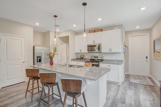 kitchen featuring appliances with stainless steel finishes, a sink, light wood finished floors, and a kitchen bar