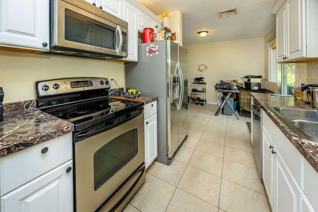 17924 W Sycamore Dr, Loxahatchee, FL 33470 - kitchen with stainless steel appliances, dark countertops, white cabinets, and a textured ceiling