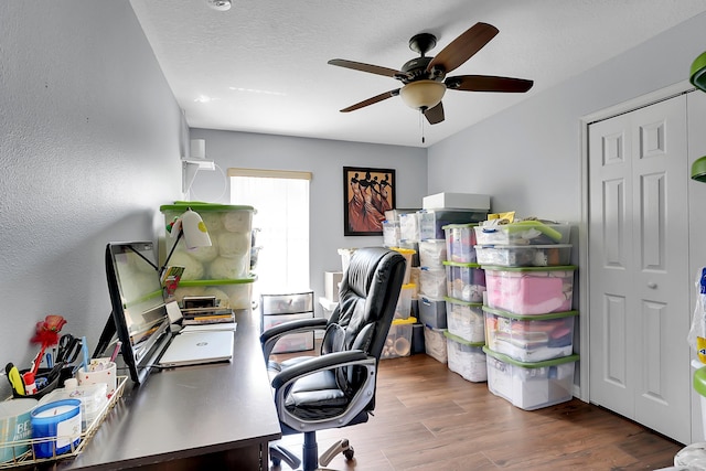 office with a textured ceiling, a textured wall, ceiling fan, and wood finished floors