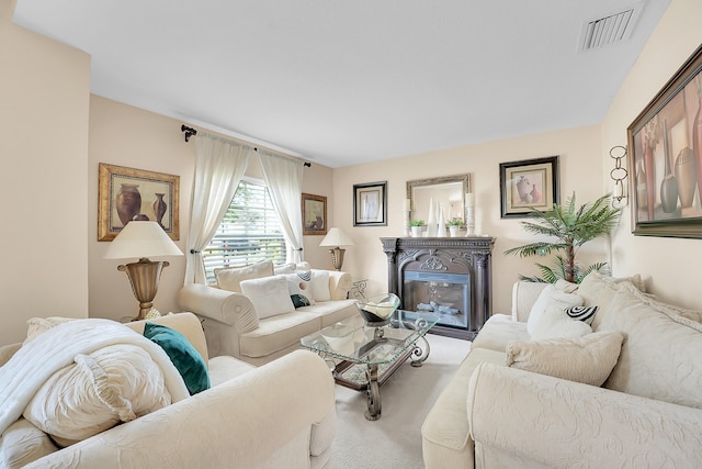 living room featuring visible vents, a glass covered fireplace, and light colored carpet