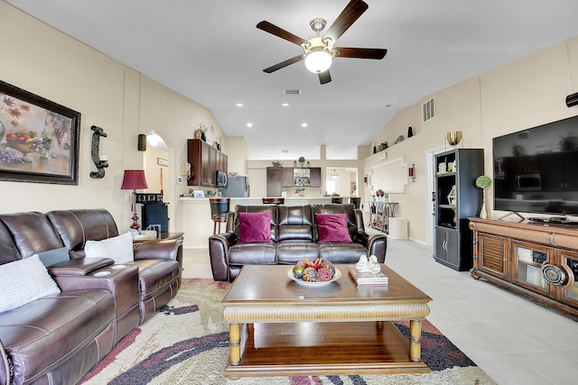 living room featuring light tile patterned flooring, ceiling fan, visible vents, and lofted ceiling