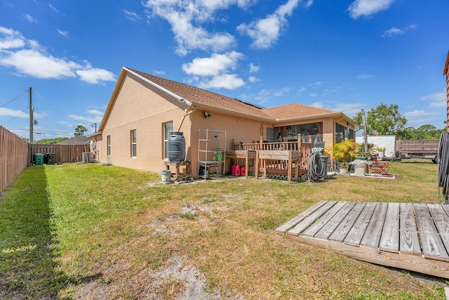 rear view of house with a lawn, a wooden deck, a fenced backyard, and stucco siding