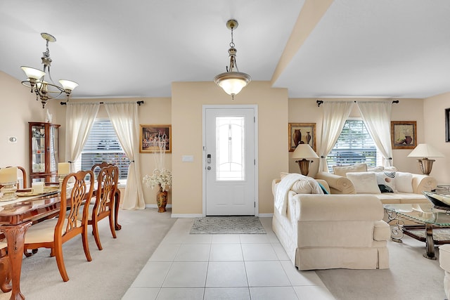 entrance foyer with light tile patterned floors, baseboards, a notable chandelier, and light colored carpet