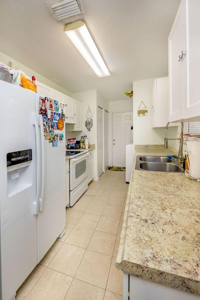 kitchen with white appliances, light countertops, white cabinetry, a sink, and light tile patterned floors