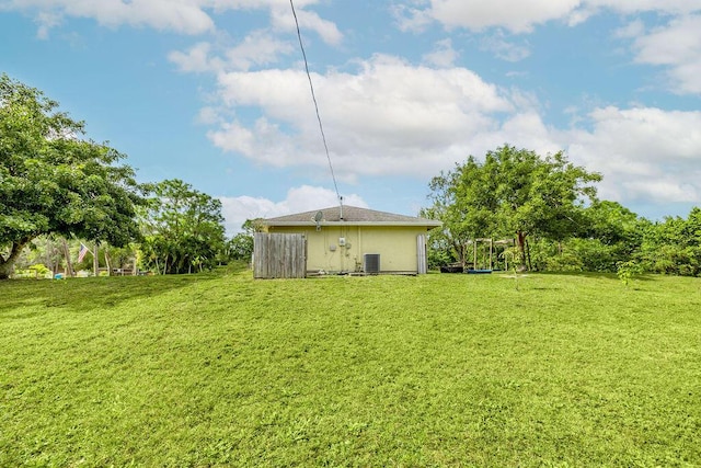rear view of property featuring a lawn and central air condition unit