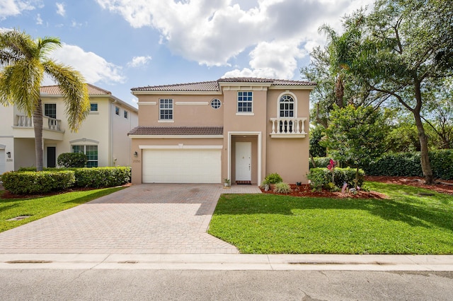 mediterranean / spanish house with a tiled roof, decorative driveway, a garage, and stucco siding