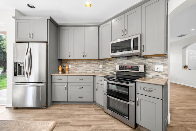 21256 Via Fiore, Boca Raton, FL 33433 - kitchen featuring appliances with stainless steel finishes, gray cabinetry, decorative backsplash, recessed lighting, and light wood-style flooring