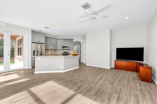 21256 Via Fiore, Boca Raton, FL 33433 - unfurnished living room with arched walkways, light wood-style floors, baseboards, a sink, and recessed lighting