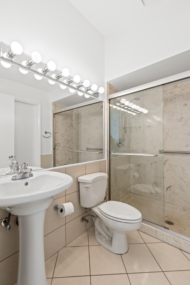 bathroom with tile patterned flooring, a sink, toilet, and a shower stall