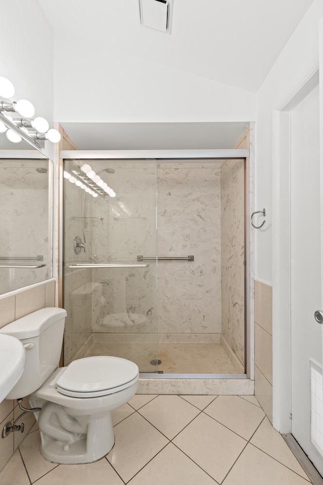bathroom with tile patterned flooring, toilet, tile walls, visible vents, and a stall shower
