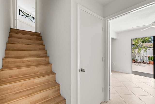 stairway featuring ceiling fan and tile patterned floors