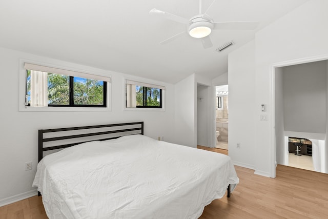 bedroom featuring ensuite bath, baseboards, wood finished floors, lofted ceiling, and visible vents