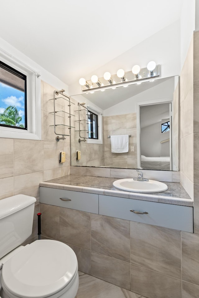 bathroom featuring vanity, tile walls, vaulted ceiling, and toilet
