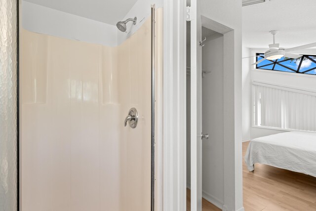 bathroom featuring a shower, a ceiling fan, baseboards, and wood finished floors