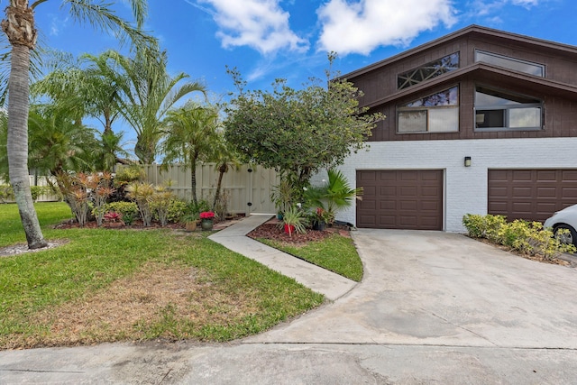 multi unit property featuring fence, brick siding, a garage, a front yard, and driveway