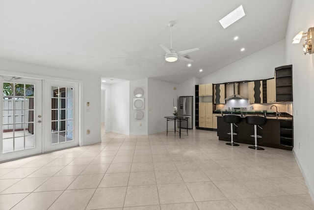 living room with ceiling fan, french doors, vaulted ceiling, light tile patterned floors, and baseboards
