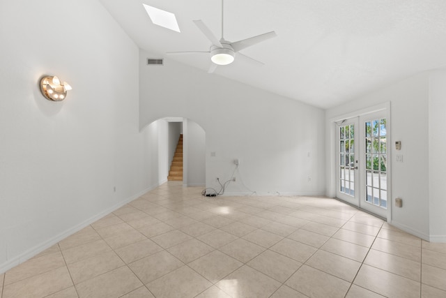 unfurnished living room with arched walkways, high vaulted ceiling, baseboards, light tile patterned floors, and visible vents